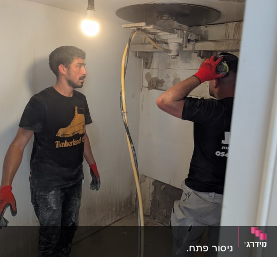 שני אנשים עובדים בחדר עם מכונת ניסור בטון